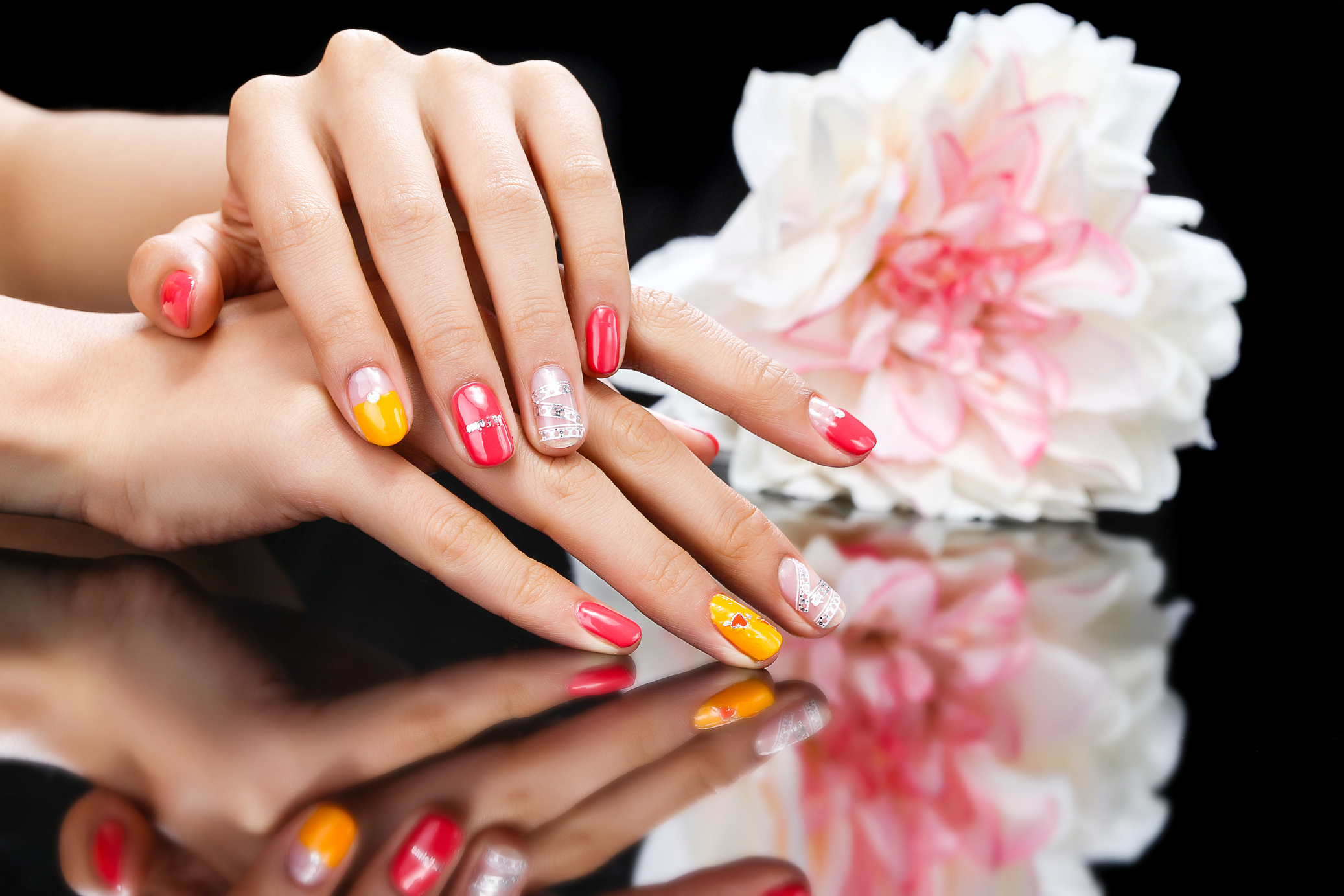 a person's hands with colorful manicured nails and a flower