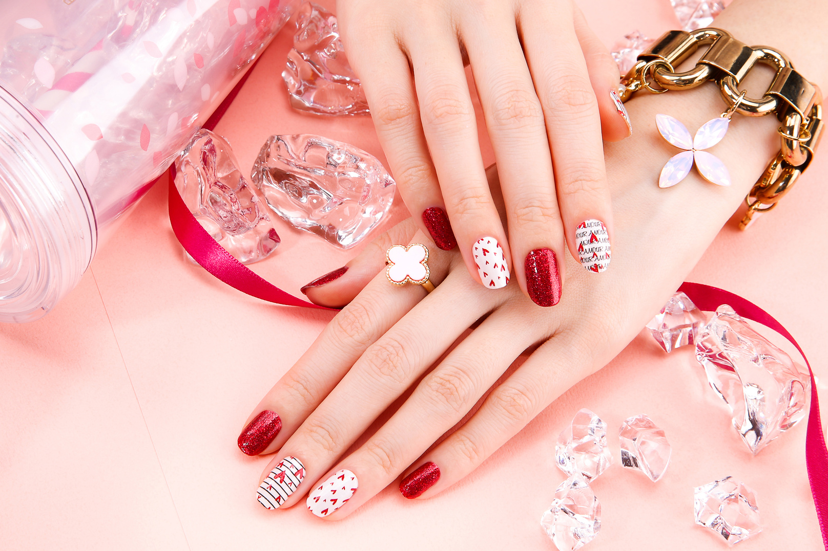 a person's hands with red and white manicured nails on pink background